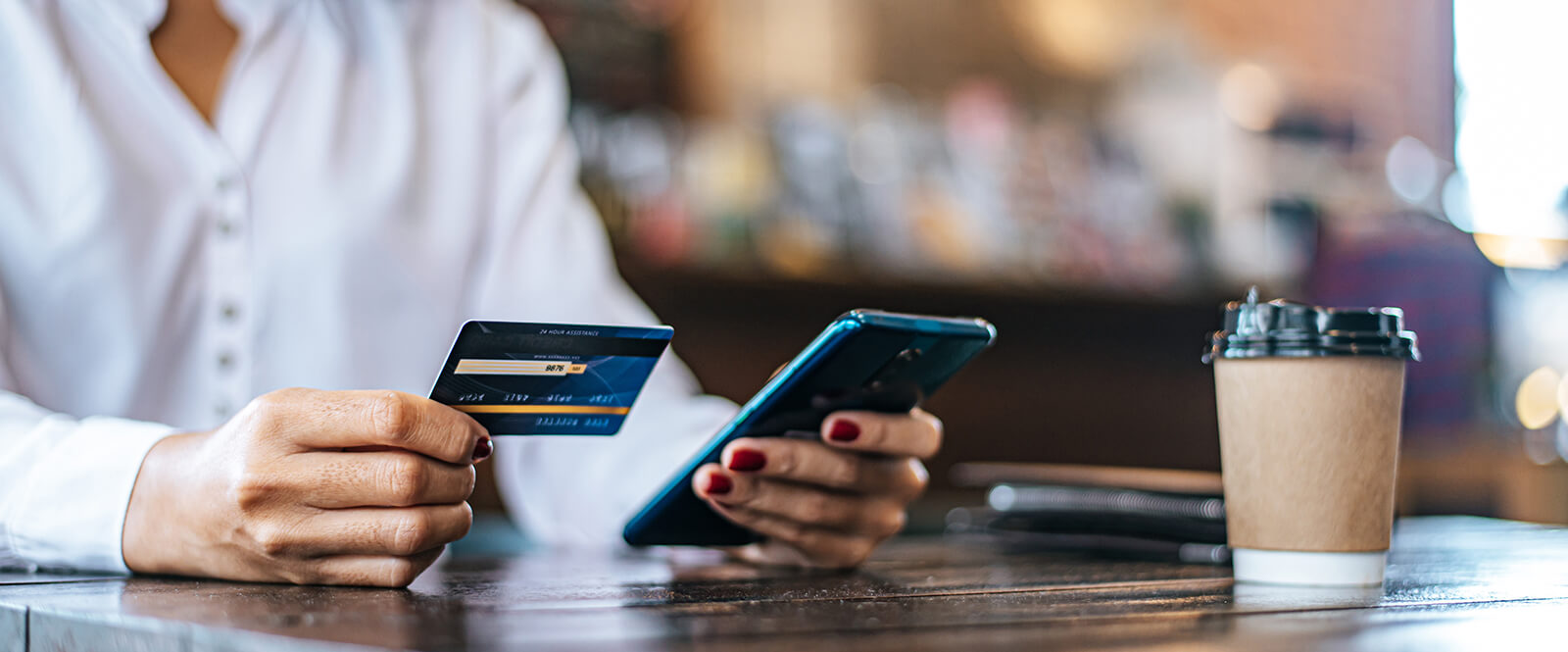Woman holding a smartphone and a credit card in a cafe