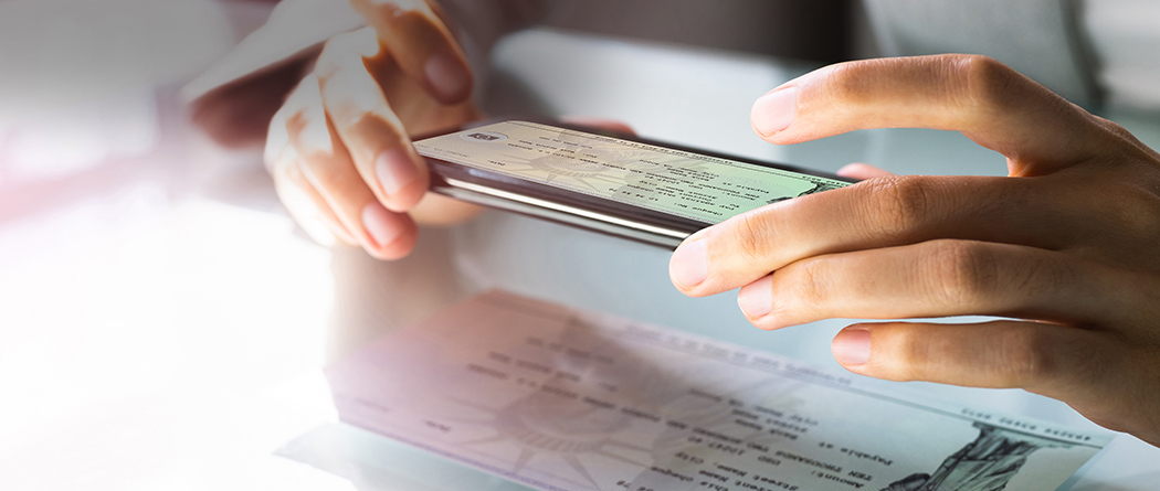 Close-up of a person taking a picture of a bank check with their smartphone