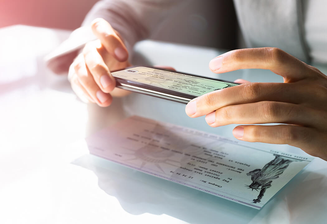 Close-up of a person taking a picture of a bank check with their smartphone